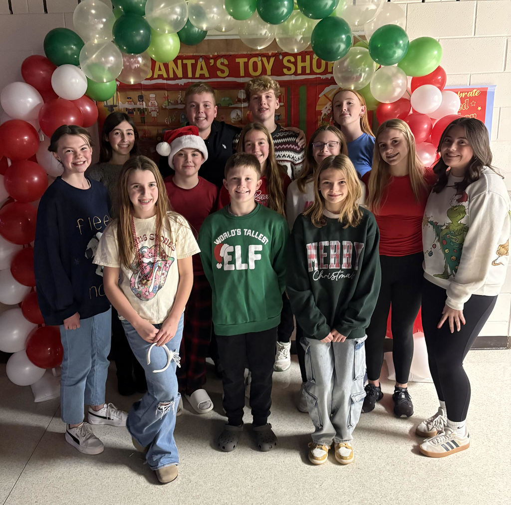 A group of students pose in front of a balloon arch at a Santa's Workshop themed dance.  