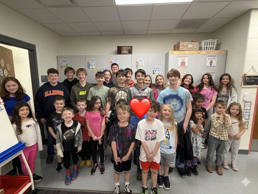 8th grade and K students pose together.