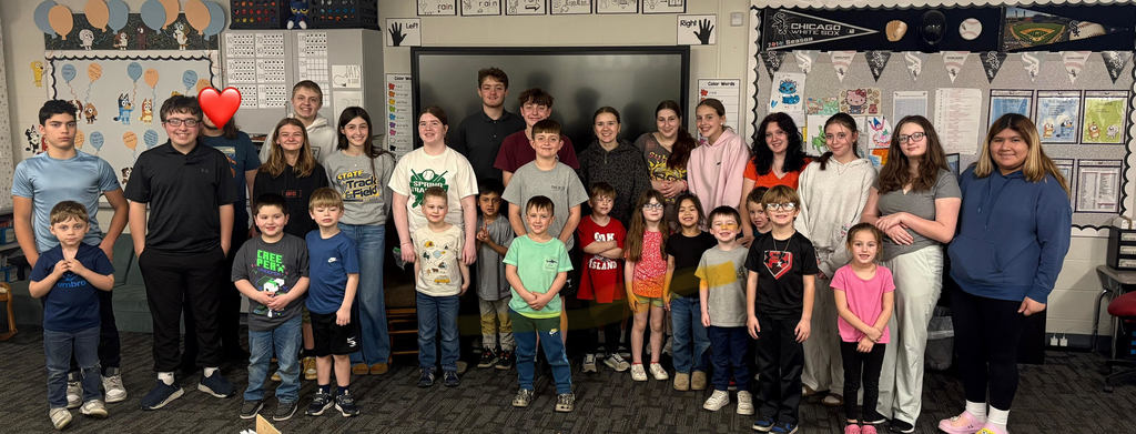 8th grade and K students pose together.