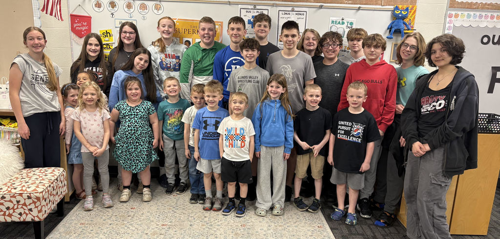 8th grade and K students pose together.