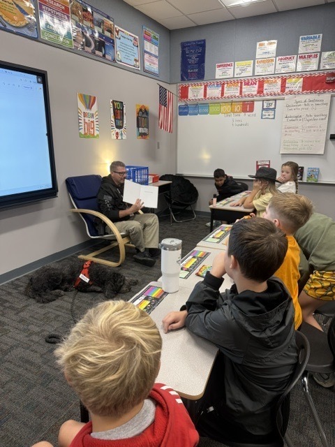 Officer Sangston and Stella reading to 4th grade