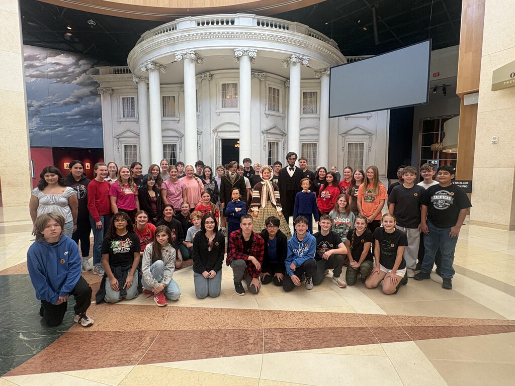 Middle school students pose in a museum.  