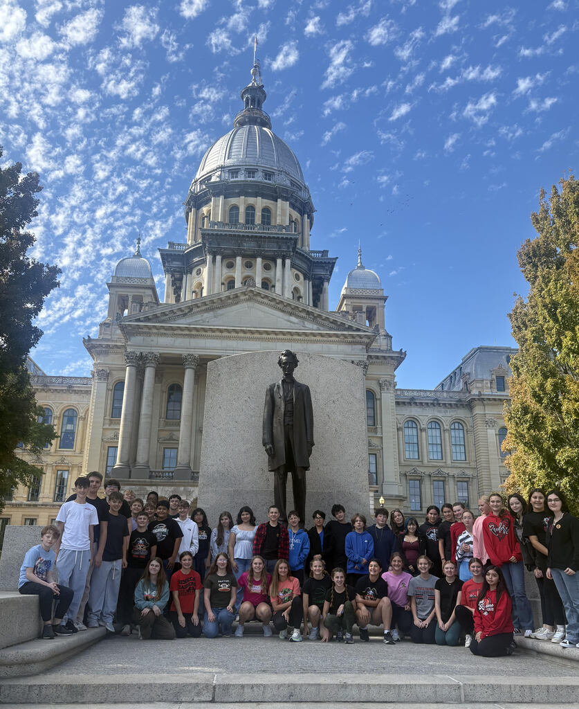 Middle school students post in front of the Illinois state capitol building.