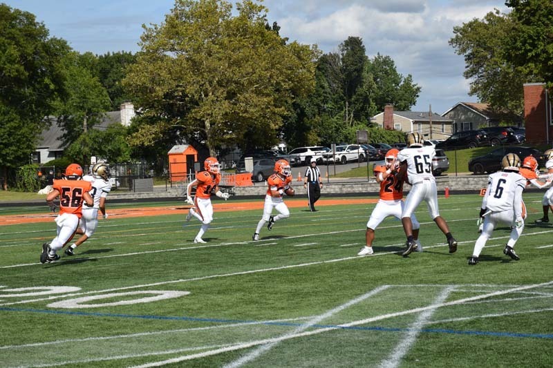 Students playing football on field.