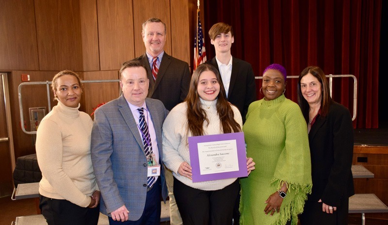 A group of young adults, stand in a theater's front stage seating area