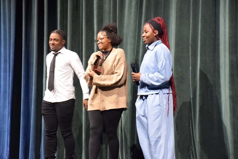 Students on stage holding microphones.