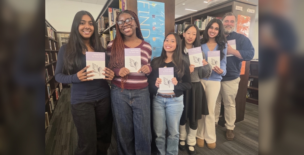 A group holds books in a library, displaying the title Hold This to Your Ear.