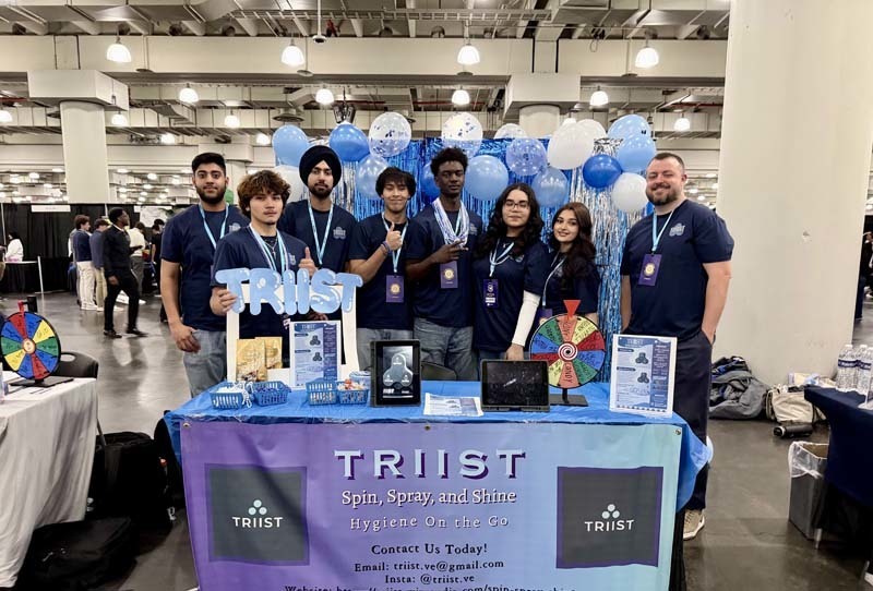Students standing in  front of TRIIST table.