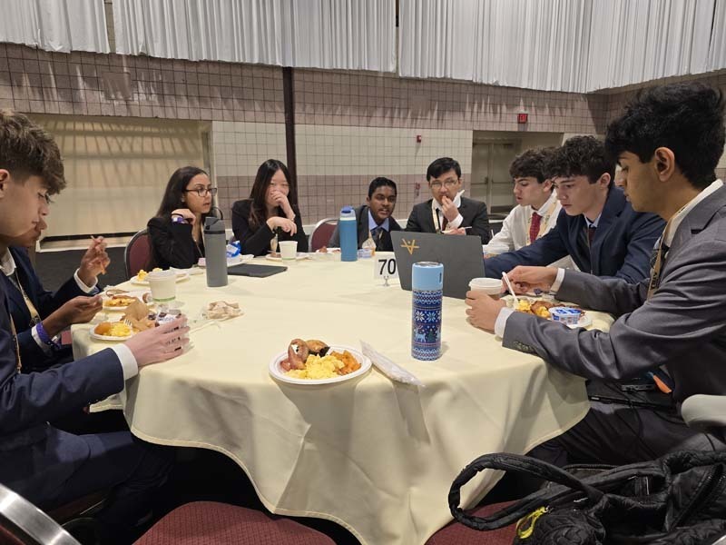 Well-dressed students eating dinner together at a table.