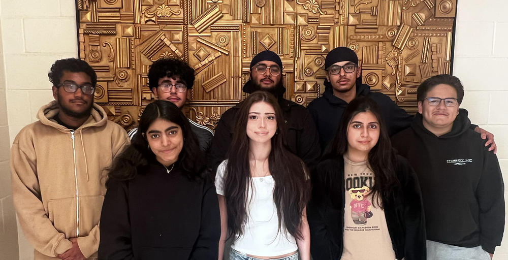 students in hall in front of gold mural