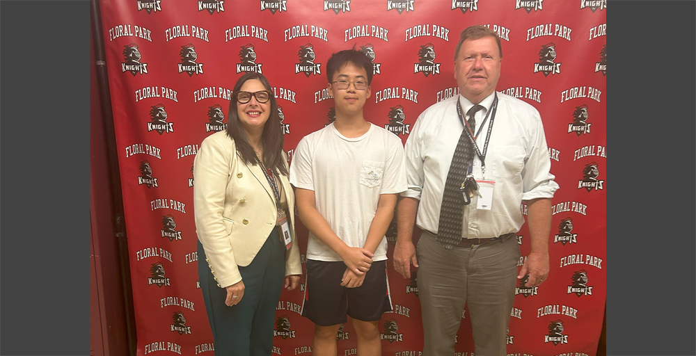 students in front of red banner with a staff member