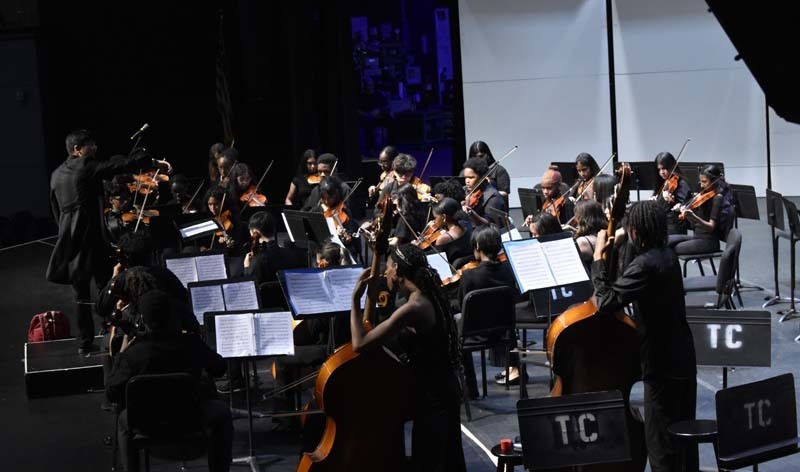 Student orchestra performing on stage.