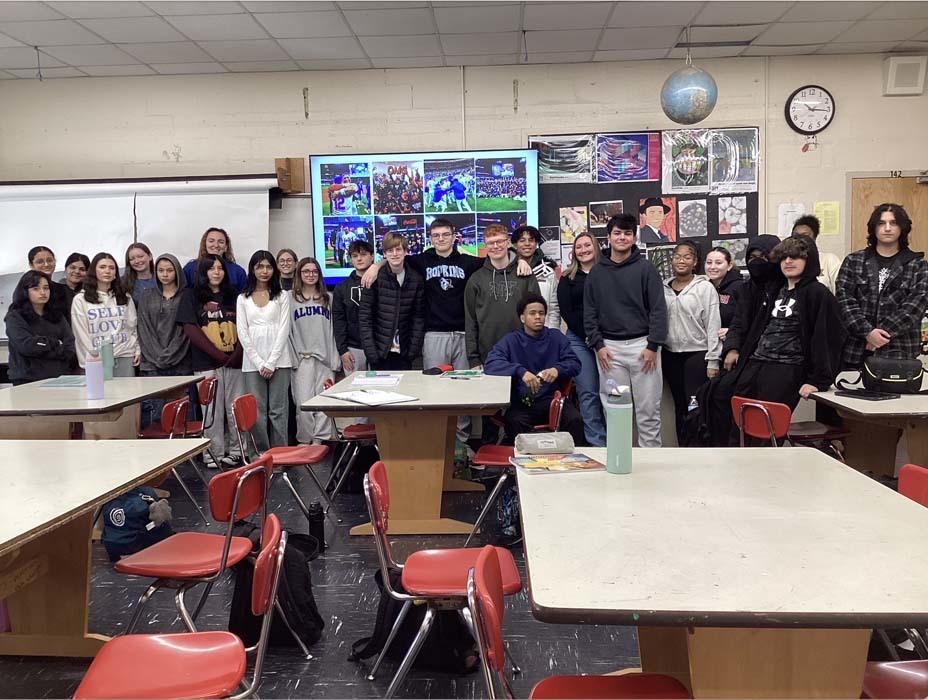 Student group picture in front of Smartboard in classroom.