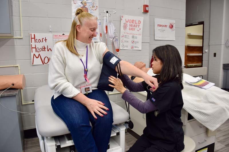 Student taking adult's blood pressure.