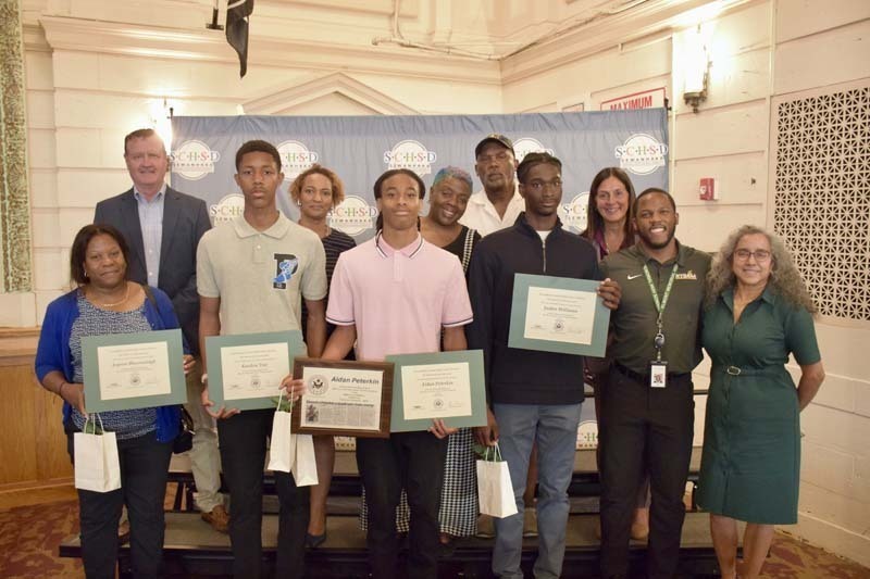 Students holding awards, smiling with BOE members.