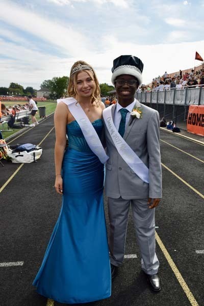 Homecoming king and queen smiling together on track.