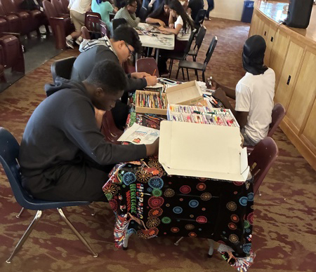 People drawing at a table with art supplies