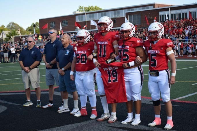 Football players with coaches on field.
