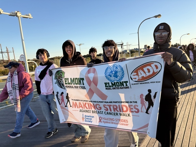 A group holds a banner for the Making Strides Against Breast Cancer walk event.