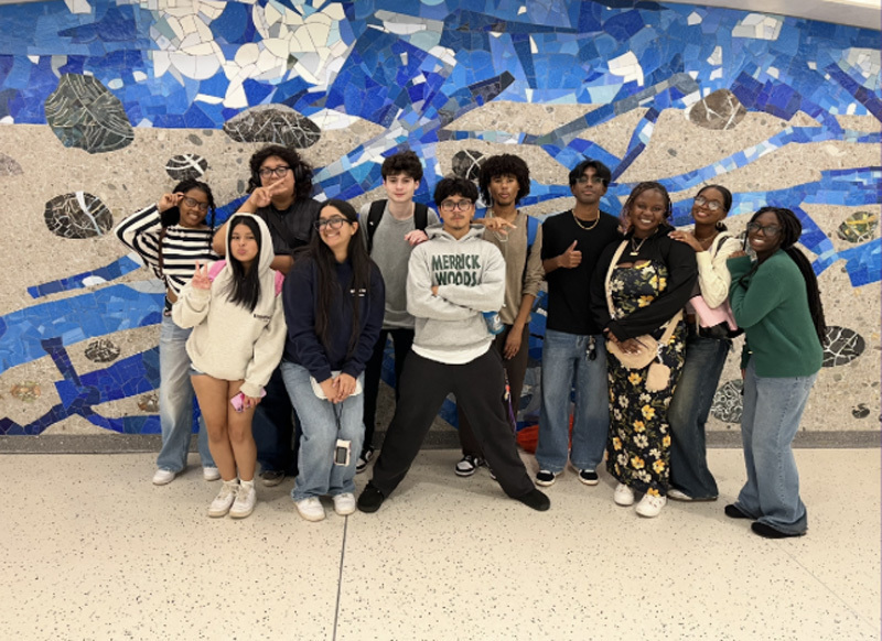 students in hall in front of mural