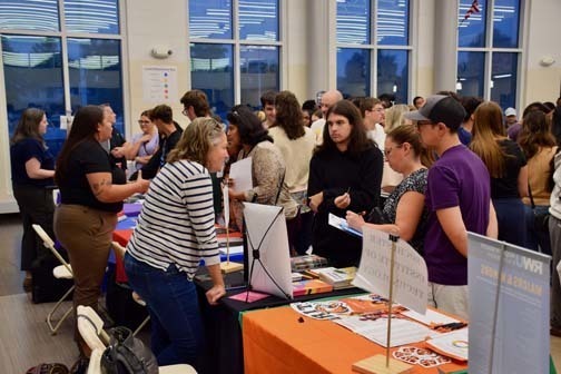 Students listening to older person talk at table.