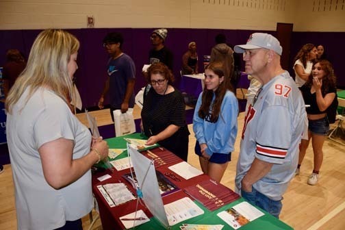 Students listening to older person talk at table.