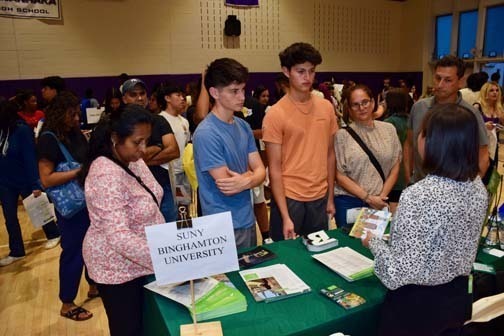 Students listening to older person talk at table.