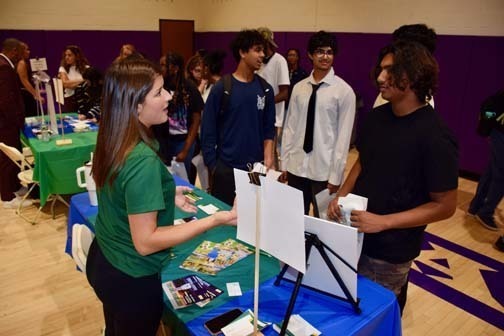 Students listening to older person talk at table.