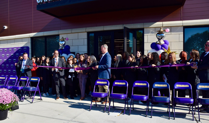 students in ribbon cutting outside building