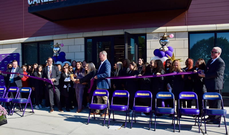 students in ribbon cutting outside building