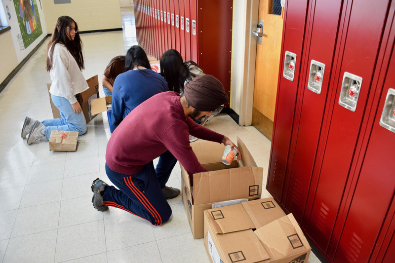  group of young adults boxing items in hall