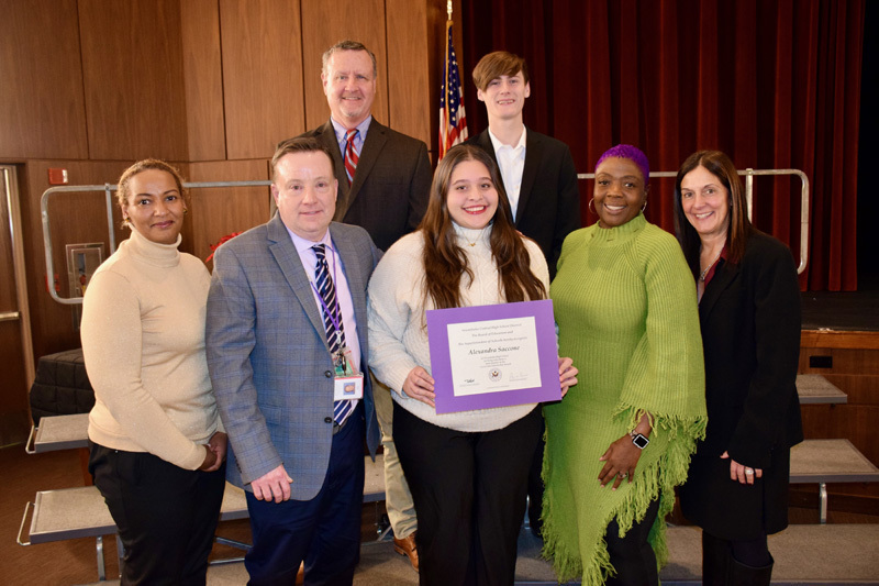 A group of young adults, stand in a theater's front stage seating area