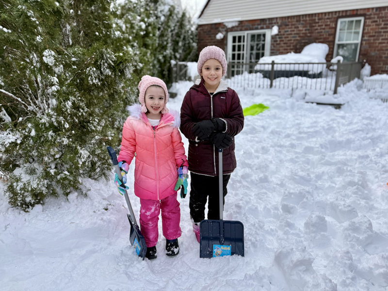 2 kids with snow shovels in the snow