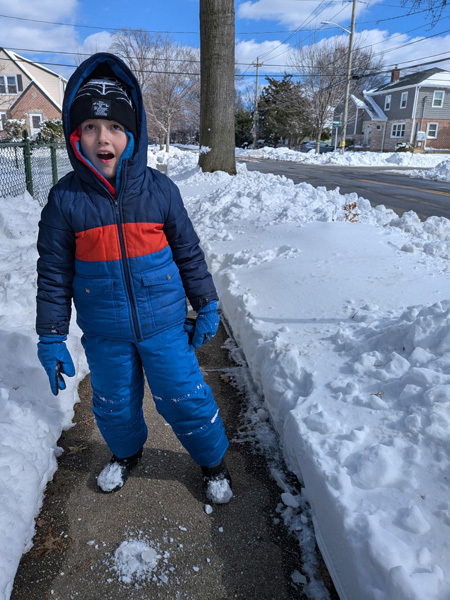 student in snow on his sidewalk
