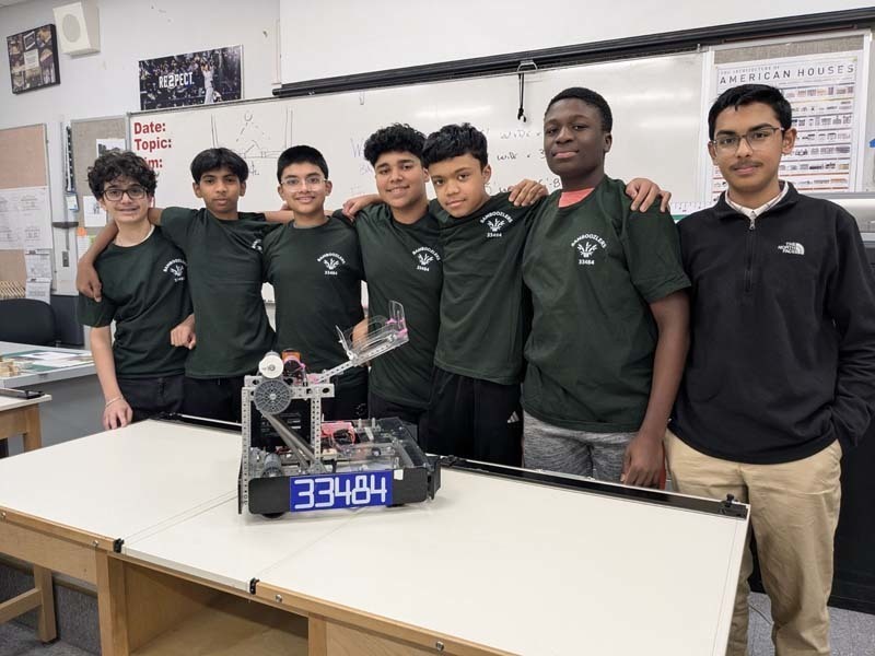 Students smiling together in front of table.