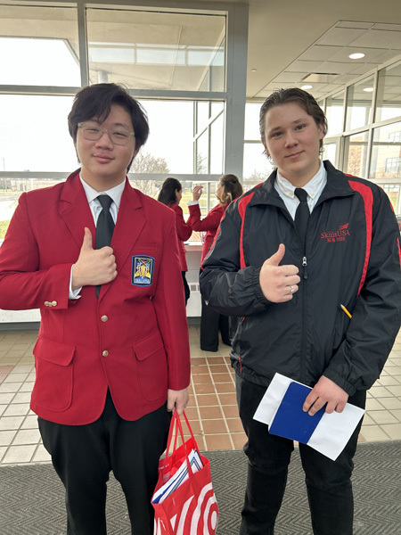 Three young women in red blazers with patches stand smiling in front of a SkillsUSA Long Island Area VI backdrop, exuding pride and confidence.