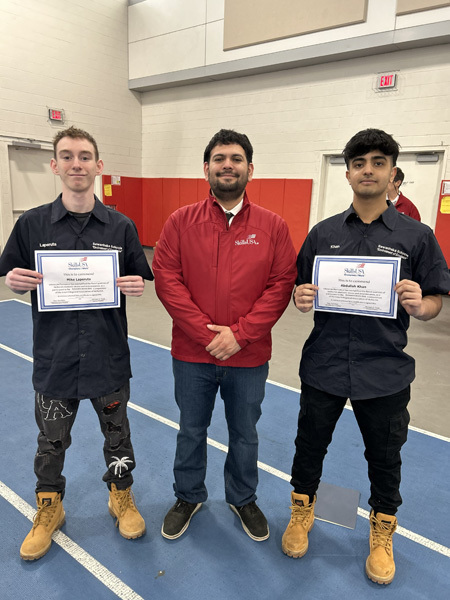 Three young women in red blazers with patches stand smiling in front of a SkillsUSA Long Island Area VI backdrop, exuding pride and confidence.