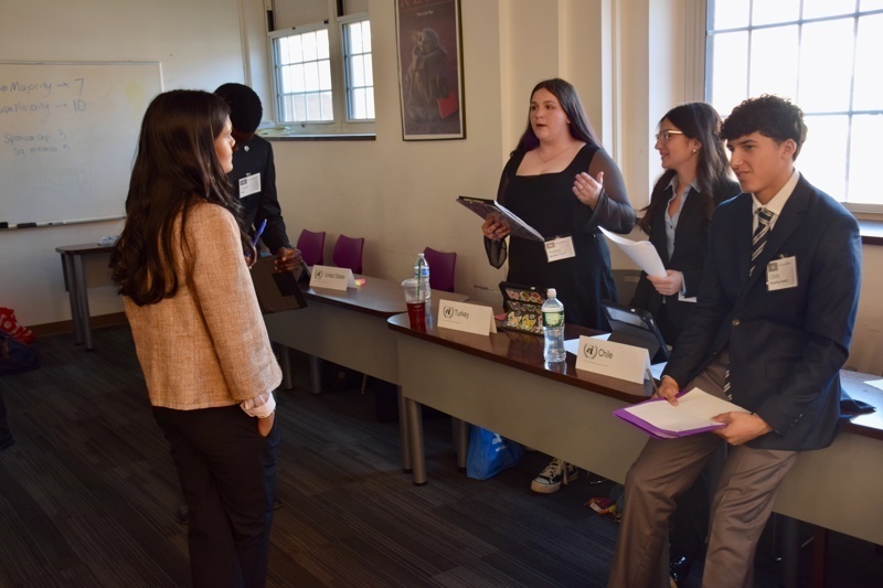 during a conference or workshop, with students seated and taking notes.