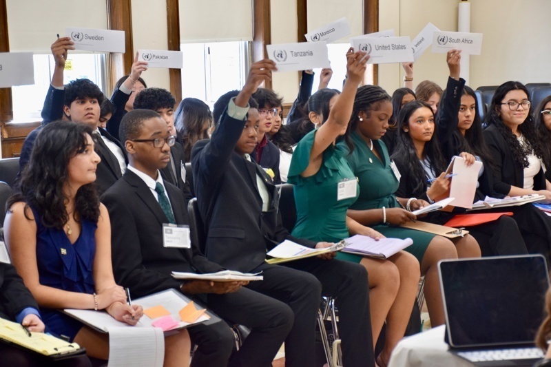 during a conference or workshop, with students seated and taking notes.