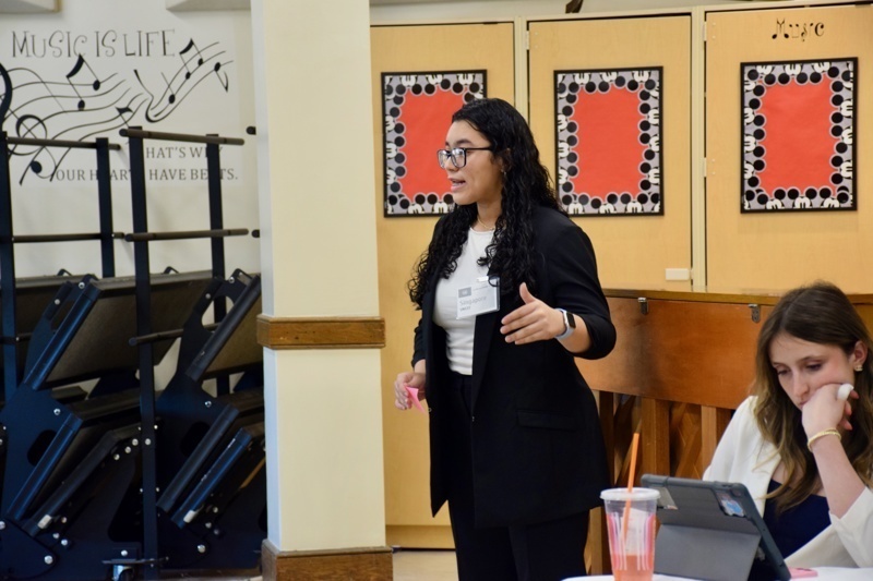 during a conference or workshop, with students seated and taking notes.