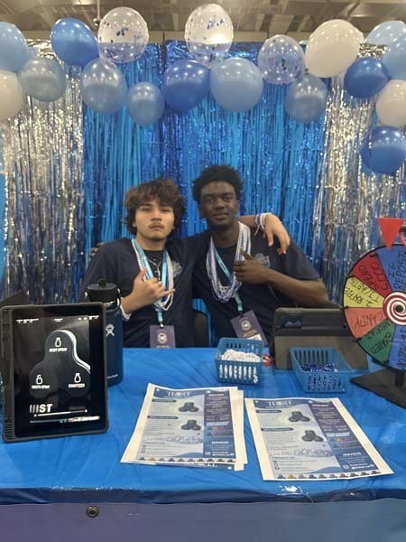 Students standing in front of TRIIST table.