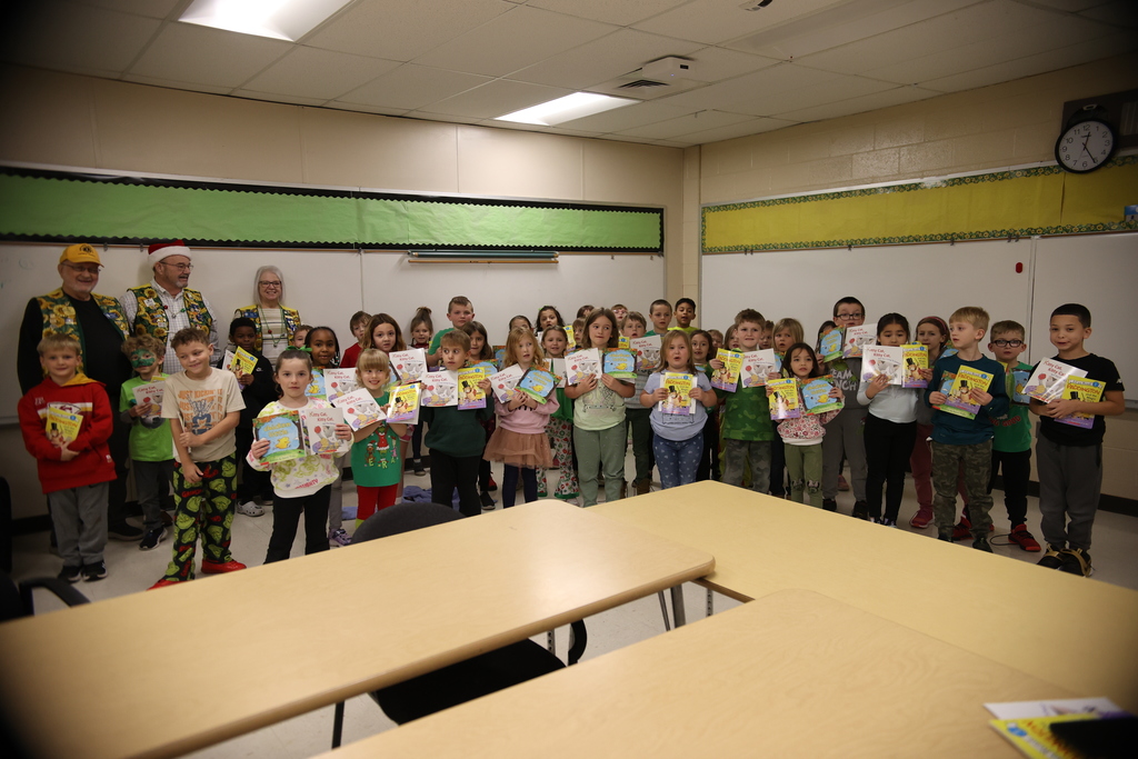 Group Picture of Students holding books with 3 members of the Sunflower Lions Club in the back row.