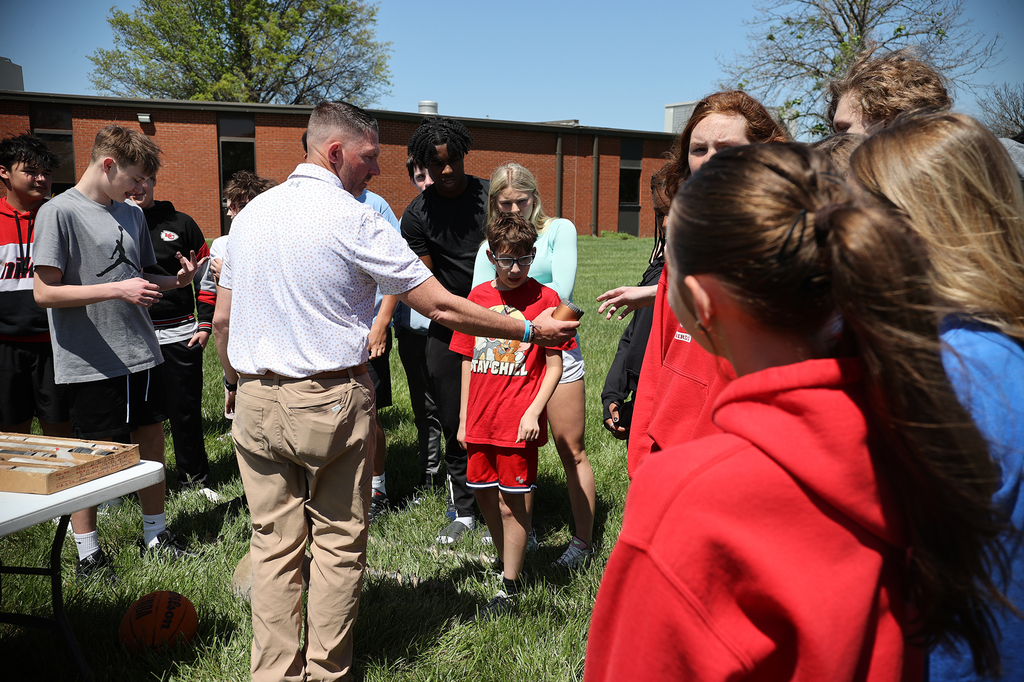 Students gather closely as a KDOT staff member passes around a rock core sample for hands-on observation.