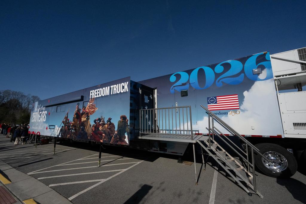 A mobile museum with the words Freedom Truck 2026 Freedom 250 is shown with a line of students waiting to enter to tour the museum. 