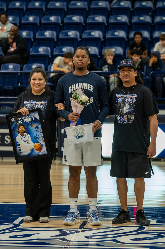 teenage boy and parents standing on basketball court