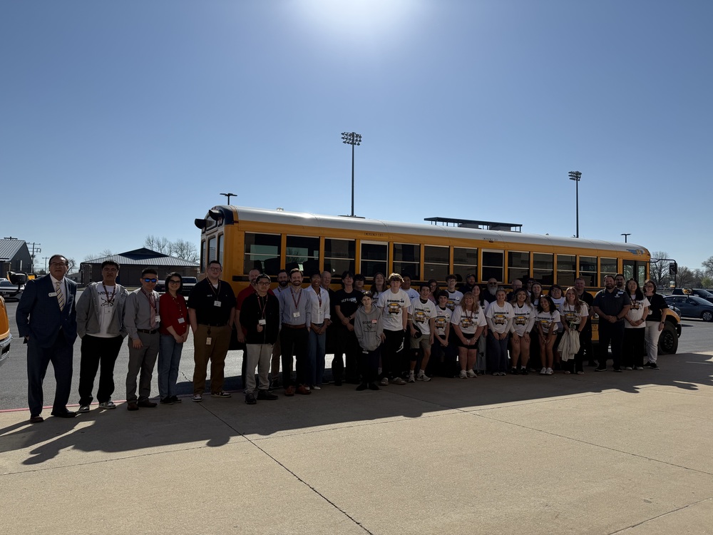 group of teens  in front of school bus