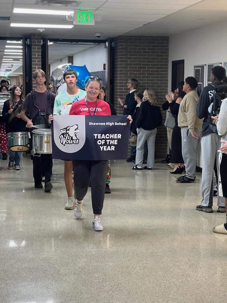 Teacher walking through hall carrying sign