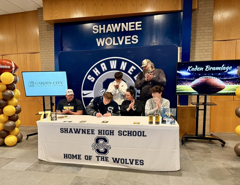high school senior signing celebration with others clapping