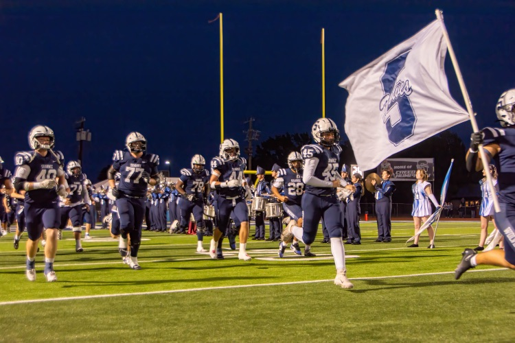 football players running with Shawnee flag