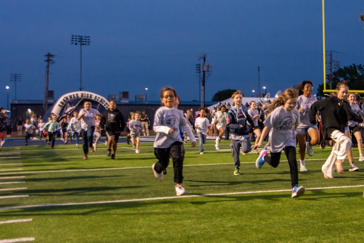 elementary students running out of tunnel on field